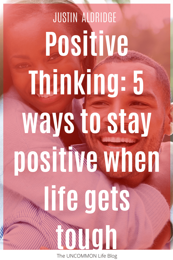 Man and woman smiling in the background with the text, "Positive Thinking: 5 ways to stay positive when life gets tough" in white font on a red overlay
