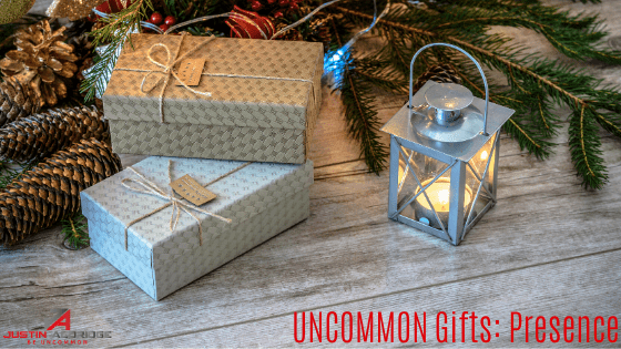Beautifully wrapped presents and a lantern sitting under a Christmas tree with the words "UNCOMMON Gifts: Presence" in the bottom right corner in red font