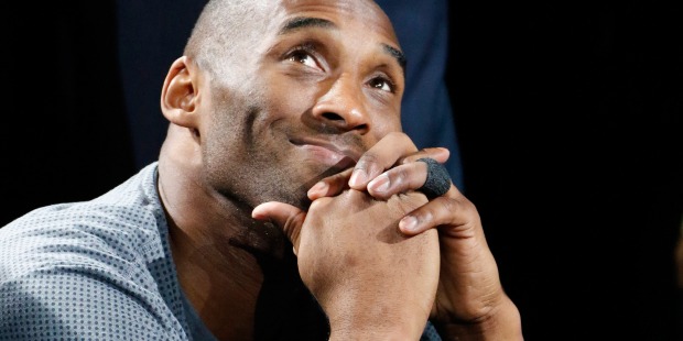Kobe Bryant starting up and smiling with his chin resting on his hands.