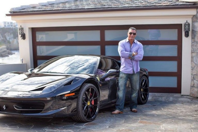 Ed Mylett standing with his arms crossed next to an exotic sports car.